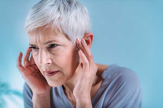 Woman holding her ears trying to stop the ringing.