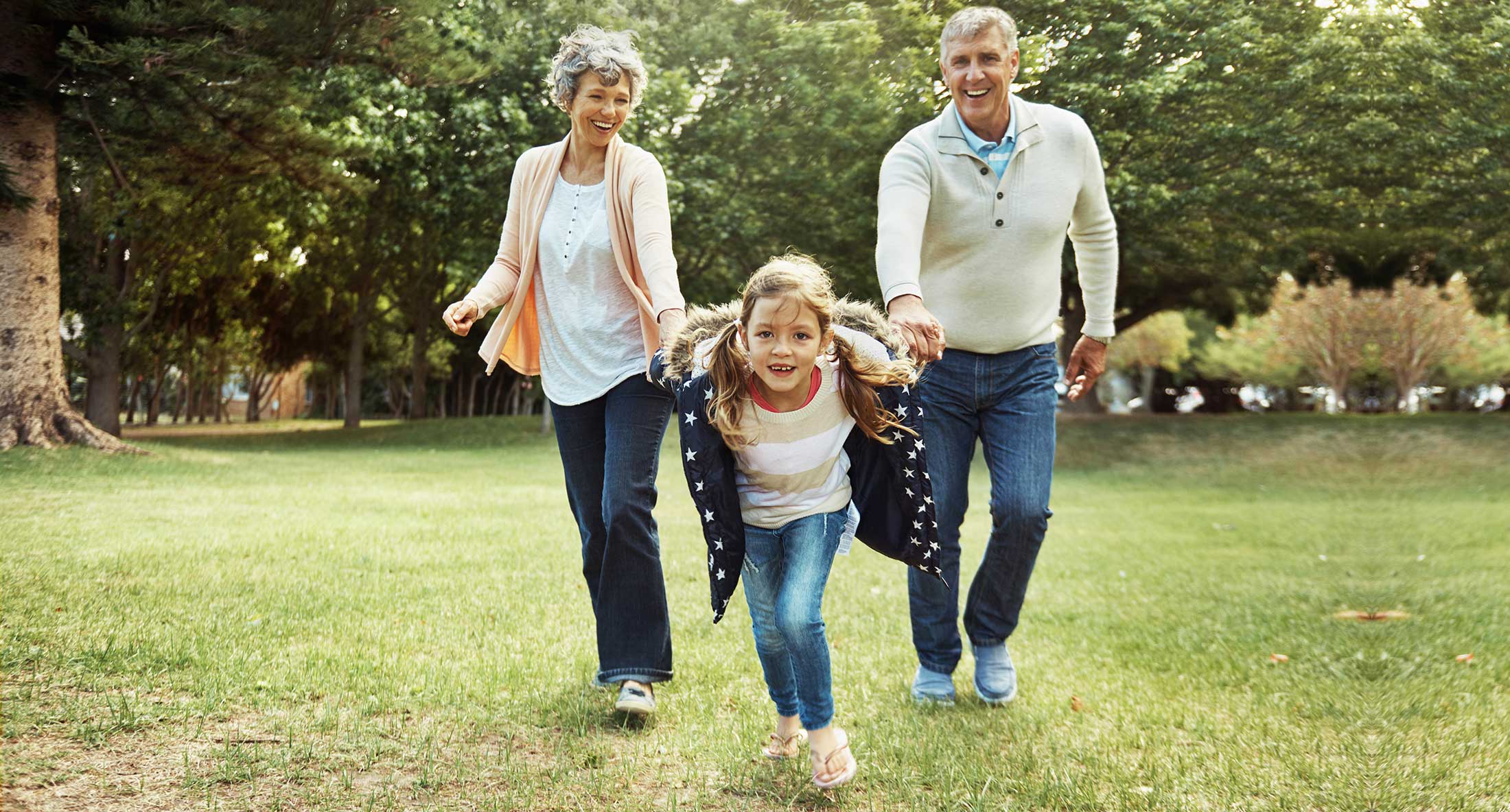 Grandparents playing with granddaughter in a park