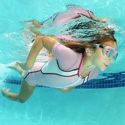 Girl swimming underwater with custom ear plugs.